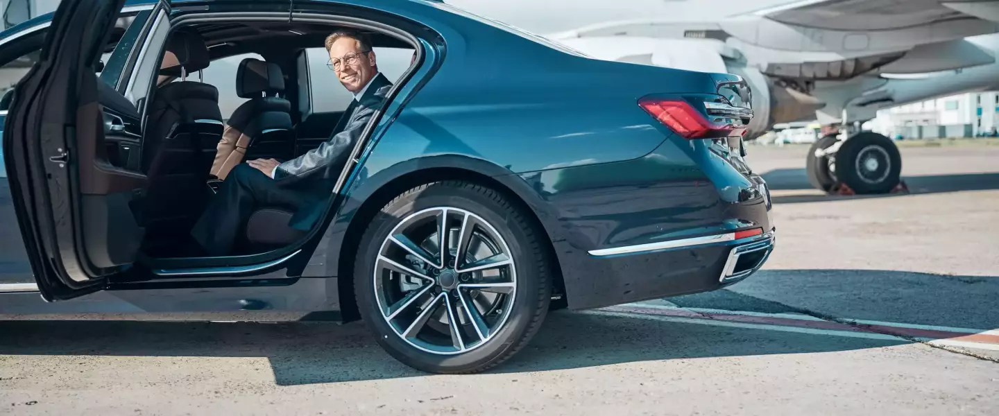 smiling-mature-businessman-in-car-near-plane-2021-09-03-21-03-08-utc-min